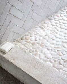 a white toilet sitting on top of a stone floor next to a bath tub covered in pebbles