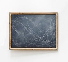 a blackboard with white writing on it in front of a white wall and wooden frame