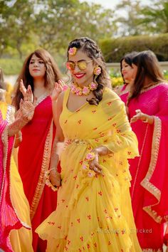 a woman in yellow and red sari dancing with other women