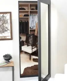 an open closet with clothes on hangers and a chair in the room next to it