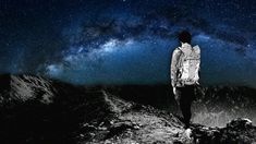 a man standing on top of a mountain under a night sky