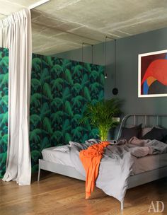 a bed sitting in a bedroom next to a green wall with palm leaves on it