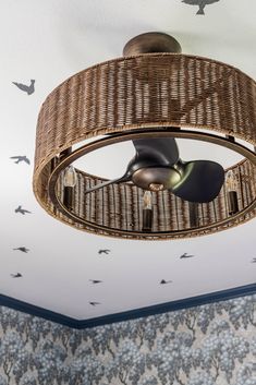 a wicker ceiling fan hanging from the ceiling in a room with birds flying around