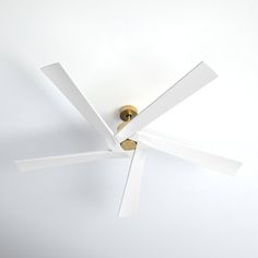 a ceiling fan with four white blades on it's face and two gold handles