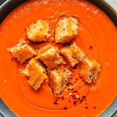 a bowl filled with tomato soup and croutons on top of it's side