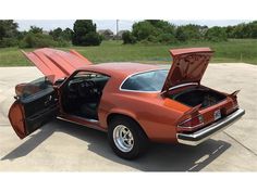 an orange car with its hood open and it's trunk opened in the driveway