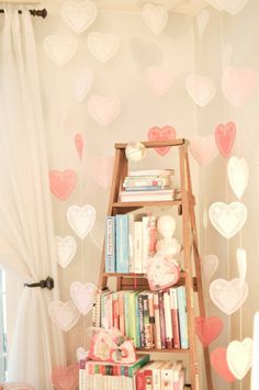 a bookshelf filled with lots of books in front of a wall decorated with hearts