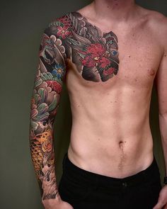 a man with tattoos on his chest and arm is standing in front of a wall