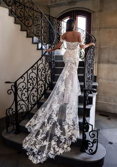 a woman in a wedding dress is standing on the stairs with her back to the camera