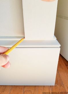 a person is holding a pencil in front of a white refrigerator with the door open