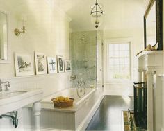 a bathroom with a tub, sink and pictures on the wall