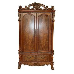 an ornate wooden armoire with carvings on the top and bottom panel, in brown wood