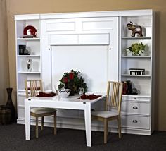 a white table and chairs in front of a bookcase with shelves on the wall