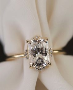 an engagement ring with a cushion cut diamond surrounded by pave diamonds on a white cloth