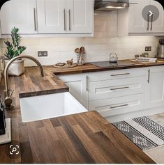 a kitchen with white cabinets and wood counter tops, an island style sink and stainless steel faucet