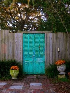 a green door is in the middle of a brick walkway with potted plants on either side