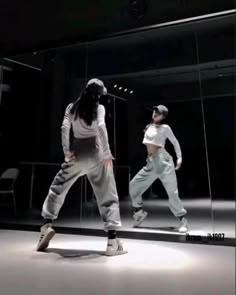 two people standing in front of a mirror with one person wearing white and the other is dancing