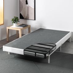 a bed frame with no mattress on it in a room next to a table and chair