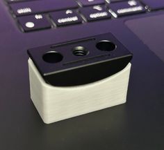 a small black and white object sitting on top of a table next to a laptop computer