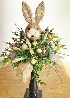 a vase with some flowers in it and a stuffed animal on top of it's head