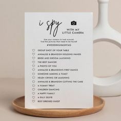 a white sign sitting on top of a wooden plate next to a vase and a cup