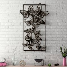 a white brick wall with a metal butterfly sculpture hanging on it's sideboard