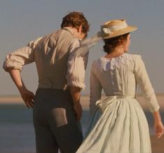 a man standing next to a woman on top of a beach