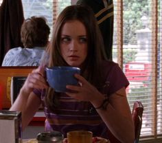 a woman sitting at a table with a cup in her hand