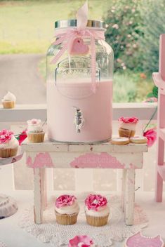 cupcakes are sitting on a table near a jar with a pink bow around it