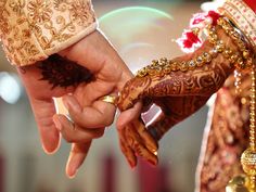 two hands holding each other while wearing gold jewelry