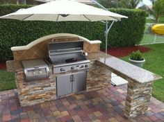 an outdoor bbq grill with umbrella over it