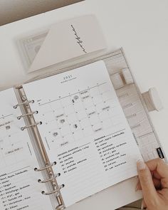 a person holding a planner in their hand and looking at the pages on top of it