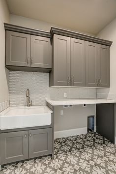 an empty kitchen with gray cabinets and white counter tops in the middle of the room