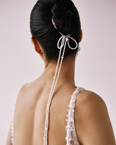 the back of a woman's head with pearls attached to her hair and wearing a white dress