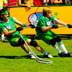 two men in green uniforms are playing tugo