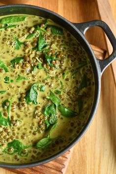 a pot filled with green food on top of a wooden table