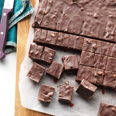 chocolate fudges cut into squares on a cutting board with a knife and napkin