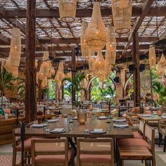 an outdoor dining area with tables, chairs and chandeliers hanging from the ceiling