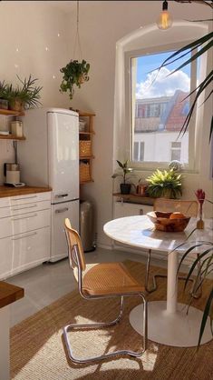 a kitchen with a table, refrigerator and window in the corner next to potted plants