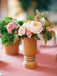 there are some flowers in the vases on the table clothed placemates