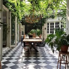 an outdoor dining area with black and white checkered tile flooring, potted plants on the table