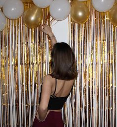 a woman standing in front of balloons and streamers with her hand on the wall