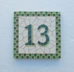 the number thirteen is made up of green and white tiles with a mosaic design on it