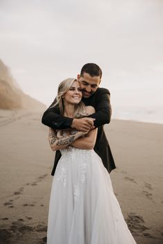 a bride and groom hugging on the beach