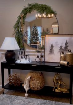 a console table with christmas decorations on it and a mirror in the corner behind it