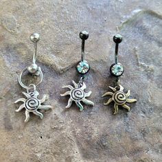 three sun and moon navel piercings are shown on top of a stone surface