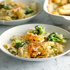 a white bowl filled with pasta and broccoli on top of a marble counter