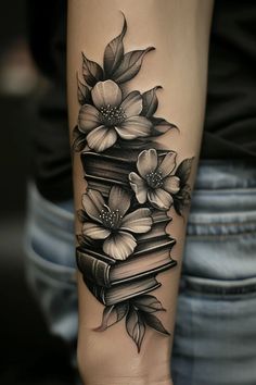 a woman's arm with books and flowers on it, while she is wearing a tattoo