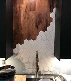 a kitchen with black cabinets and white hexagonal tiles on the backsplash