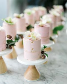 a table topped with pink cakes covered in frosting and flowers on top of each cake